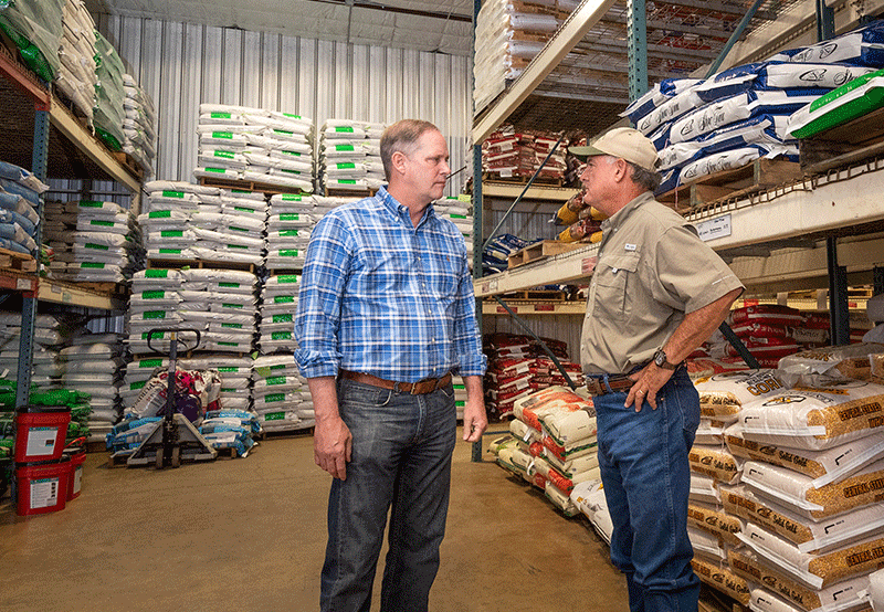 Wilton Simpson speaking with a man in a feed store.