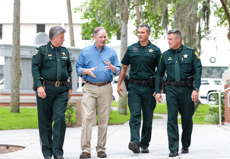 Wilton Simpson walking and talking with three sheriffs officers